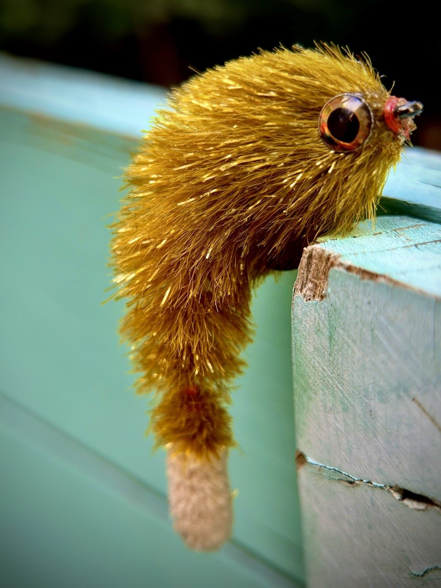 Tan baitfish-shaped fly on a seafoam workbench